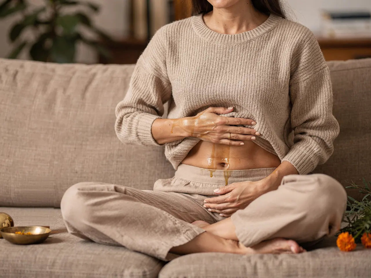 Eine Hand ruht flach auf dem Unterbauch, der Strickpullover ist leicht angehoben