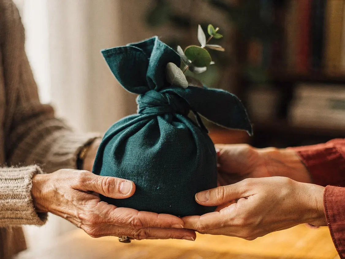 Hände knoten ein Baumwolltuch um ein Set aus Roll-ons