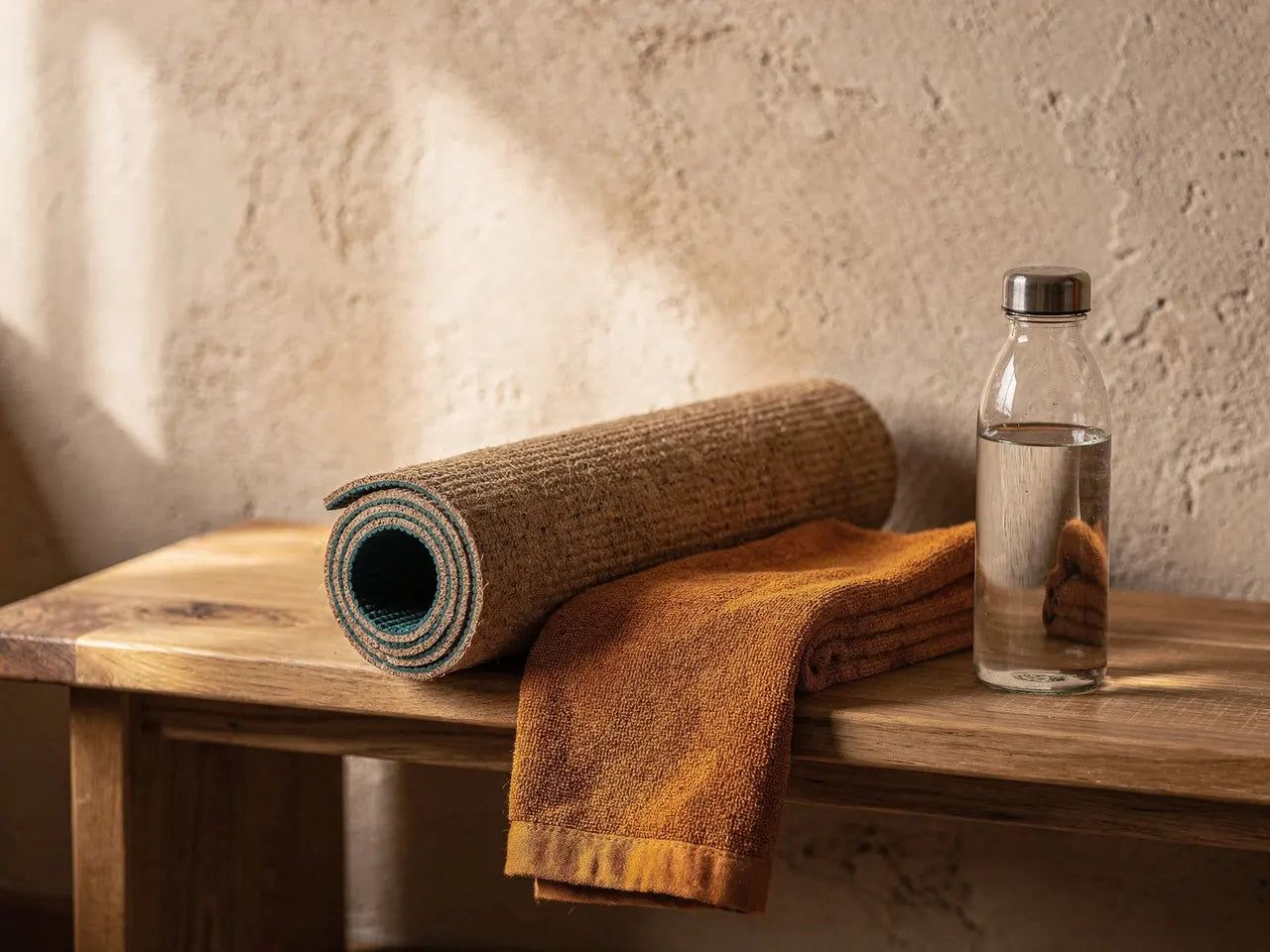 Gerollte Yogamatte und Handtuch auf einer Holzbank