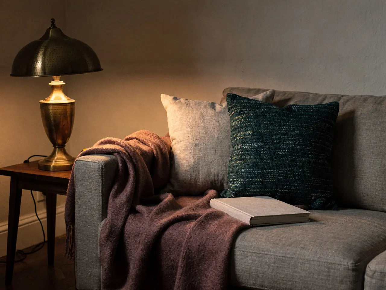 Sofaecke mit Decke, Kissen, Buch und Lampe