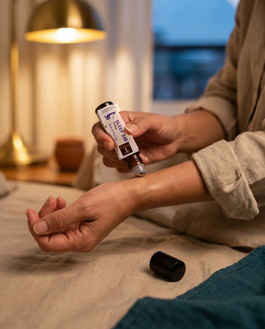 Frau rollt Nidraa abends im Bett über das Handgelenk