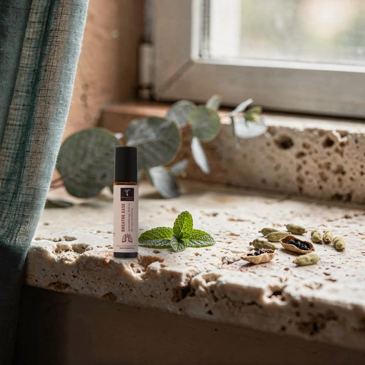 Prana Durchatmen-Roll-on auf Kalkstein am Fenster mit Eukalyptus, Pfefferminze und Kardamom