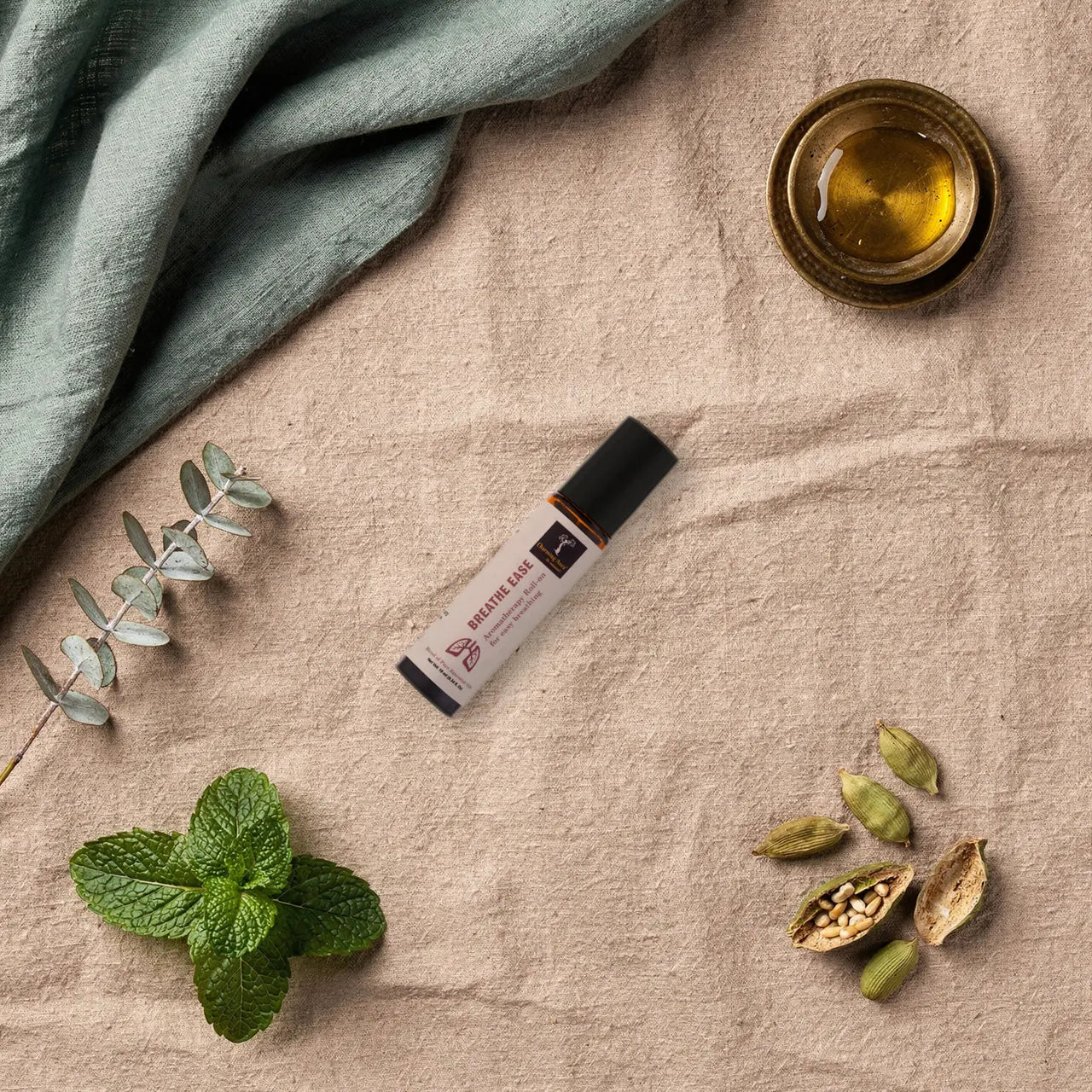 Prana Roll-on, umgeben von Eukalyptus, Pfefferminze und Kardamomkapseln