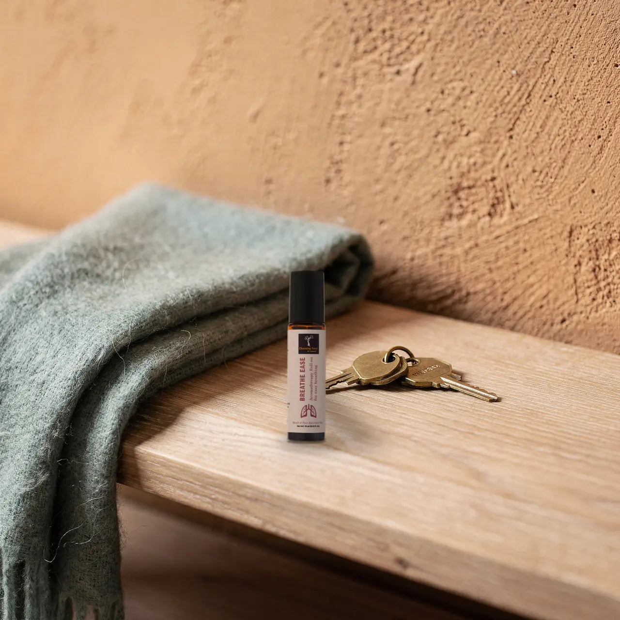 Hand hält Prana Roll-on über einem Wollschal und Schlüsseln